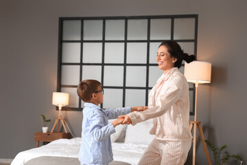 Young woman and her little son dancing in bedroom