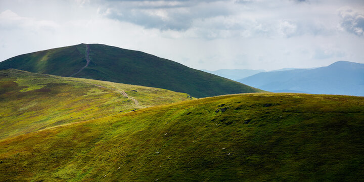 rolling hills of borzhava mountains. path through thetop of the ridge. beautiful nature scenery with grassy slopes in dappled light. wonderful summer landscape of ukrainian carpathians on a sunny day