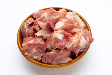 Raw pork ribs in wooden bowl on white background.