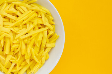 Preserved bamboo shoot in white plate on yellow background.