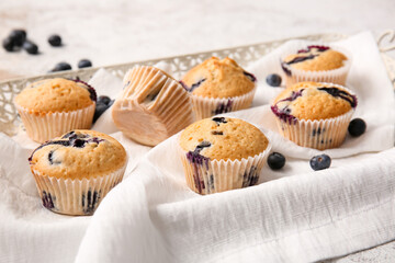 Tray with tasty blueberry muffins on light background, closeup