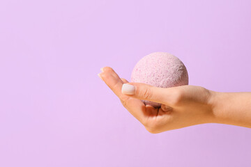 Female hand with lavender bath bomb on color background