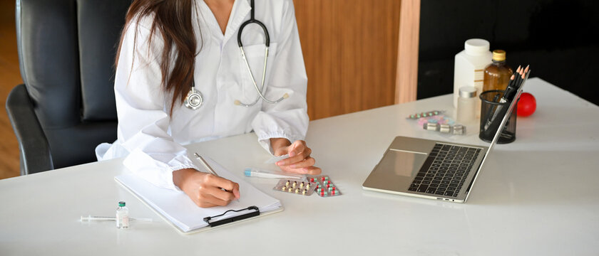 Cropped image of a female doctor or pharmacist filling out a medical form