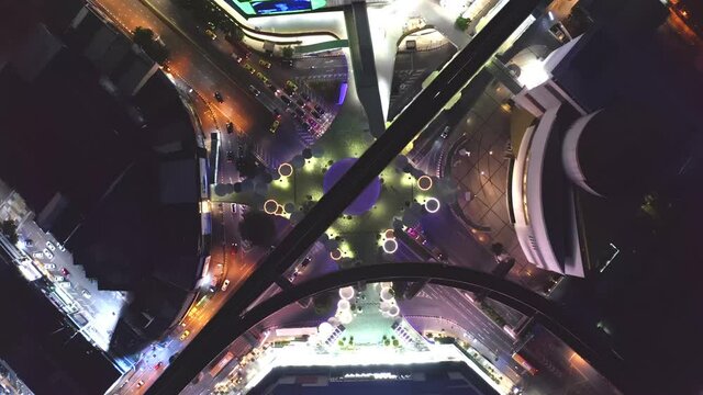Time lapse of aerial view of Siam and Skywalk aerial view in MBK Culture Center intersection or junction with cars traffic skyscraper buildings. Bangkok City in downtown at night, Thailand