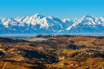 View of autumnal hills and snowy mountains in Italy.