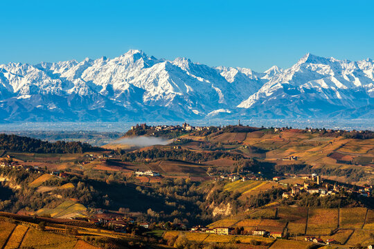 View of autumnal hills and snowy mountains in Italy.