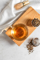 Composition with cup of tasty hojicha green tea on light background