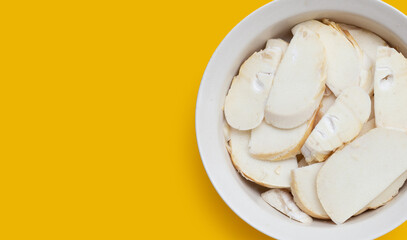 Bamboo shoots in white bowl on yellow background.