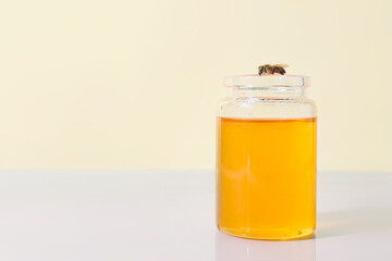 Jar of sweet honey and bee on color background