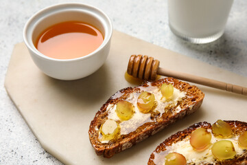Delicious toasted bread with honey, butter and grape on white background, closeup