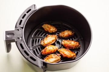 Baked chicken wings in Air Fryer on white table background. cooking for low fat control weight. food for health concept.