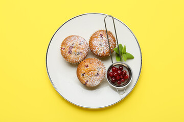 Plate with tasty cranberry muffins on color background