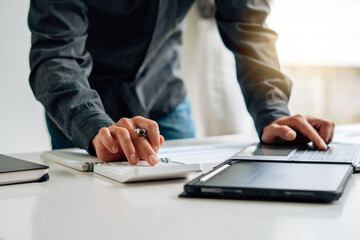 Fototapeta premium Close up hand of businessman or accountant hand holding pen working on calculator to calculate business data, accountancy document and laptop computer at office, business concept.