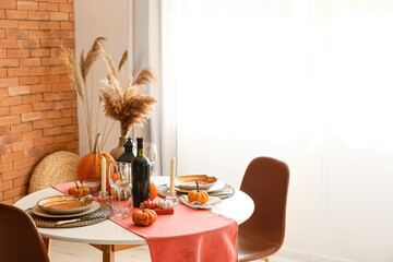 Dining table with pumpkins near window in room