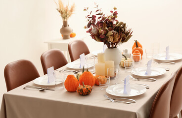 Beautiful autumn table setting with pumpkins and flowers at restaurant