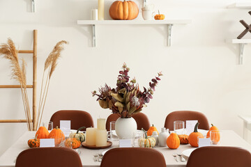 Beautiful autumn table setting with pumpkins and flowers at restaurant