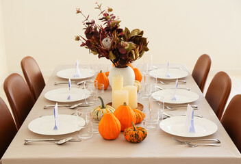 Beautiful autumn table setting with pumpkins and protea flowers at restaurant