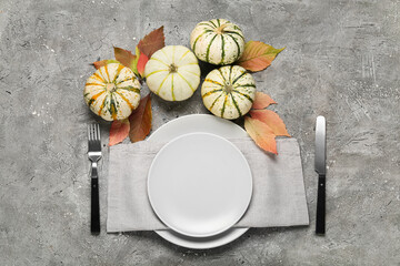 Beautiful table setting with pumpkins and autumn leaves on grey background