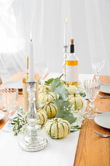 Burning candle in candlestick and beautiful autumn decor on served wooden table