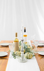 Beautiful served wooden table, burning candle in candlestick and autumn decor in room