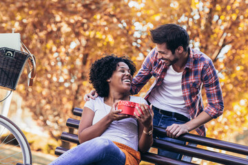 Man surprises woman with a gift in the park.