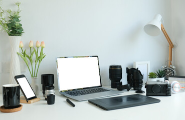 Computer laptop, smart phone, digital tablet and camera accessories on photographer workspace .