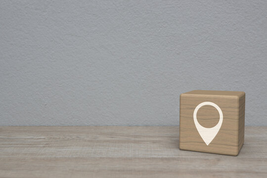 Map pin point location icon on block cube on wooden table over white wall background, Map pointer navigation online concept