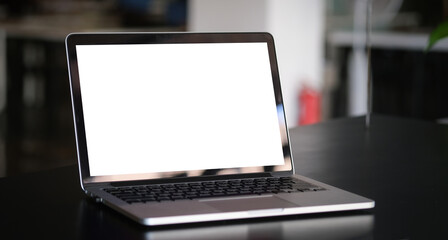 Close up computer laptop with white screen on black table in modern office.