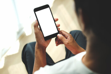 Young man sitting in living room and using smart phone.
