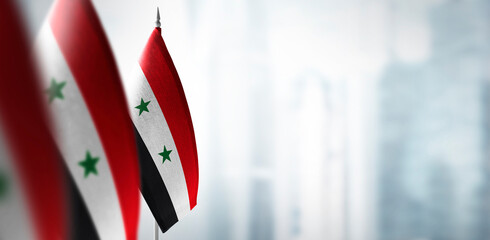 Small flags of Syria on a blurry background of the city