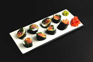 Sushi without rice served on a white plate over black background. Isolated on black.