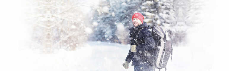 A man travels with a backpack. Winter hike in the forest. Tourist on a walk in the winter in the park.