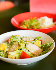 Caesar Salad served in a white bowl on the table in restaurant or diner. Traditional recipe of Caesar salad