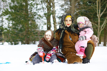 Traditional Russian holiday in early spring. Seeing off winter. Mardi gras. Family with children in the winter in the park.