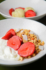 Bowl of hot oatmeal with fresh strawberries cut. Perfect as a healthy breakfast. Served with sour cream in a white bowl.