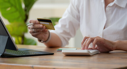 Close up woman checking bills, taxes, bank account balance and calculating credit card expenses at home.