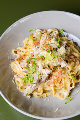 Italian tortellini pasta with cheese, sauce, and microgreens served in a white bowl. Italian cuisine concept