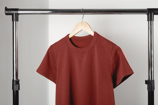 Blank red burgundy t-shirt mockup on clothes hanger. Bella canvas mock up in minimal interior.