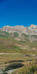 Fototapeta premium Mountains of North Ossetia, beautiful summer landscapes with blue sky and clouds. Vertical format.