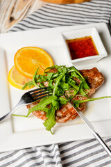Gourmet grilled steak flavoured served with fresh green arugula, orange slices and tomato sauce.
