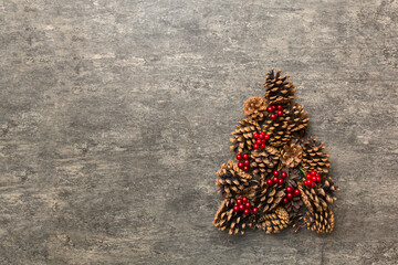 Christmas tree made from natural cones on colored background, view from above. New Year minimal concept with copy space