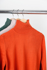 Blank turtleneck sweater mockup on clothes hanger. Bright orange ocher roll-neck with beige and...
