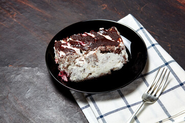 Plate with slice of tasty chocolate cake on table. Yummy dessert on on wooden background, closeup