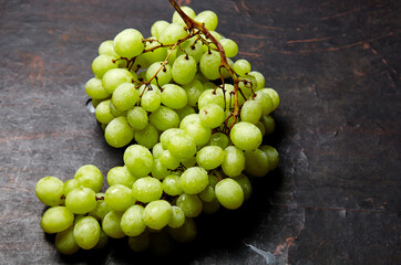 Branch of ripe green grape with water drops. Juicy grapes on wooden background, closeup. Grapes on...