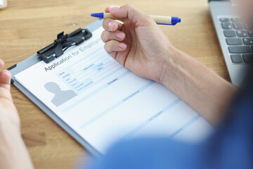 Woman holds pen and plans to fill out resume form for job