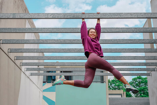 Woman stretching legs while hanging on parallel ceiling