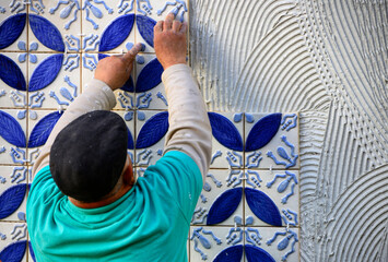 Tiler placing azulejos on adhesive cement, exterior wall, Algarve, Portugal, Europe