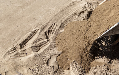A worker lays down sand for paving slabs.
