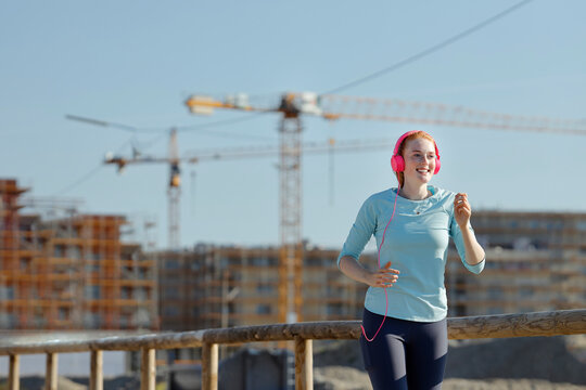 Young woman with headphones jogging at construction site