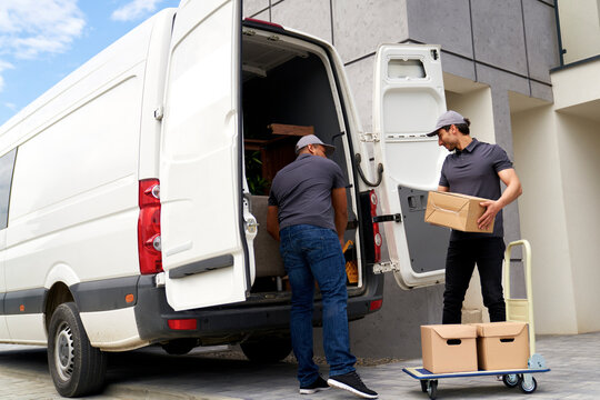 Delivery men loading cardboard box in van
